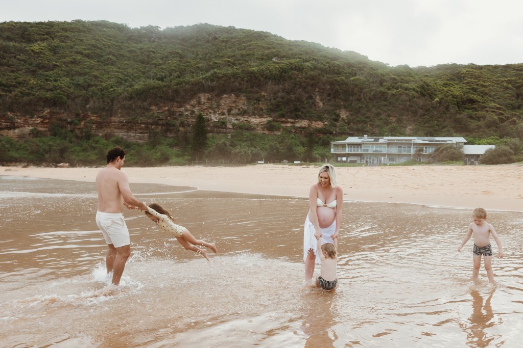 Family playing in the water at sunset on a Sydney beach during a golden hour photography session